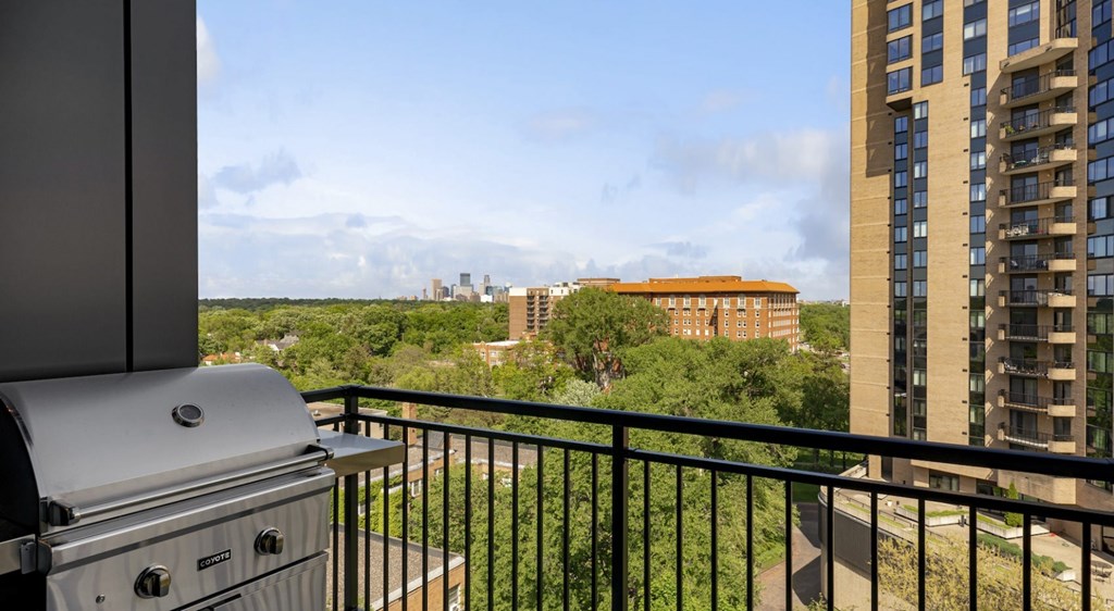 A grill is on a balcony overlooking a cityscape.