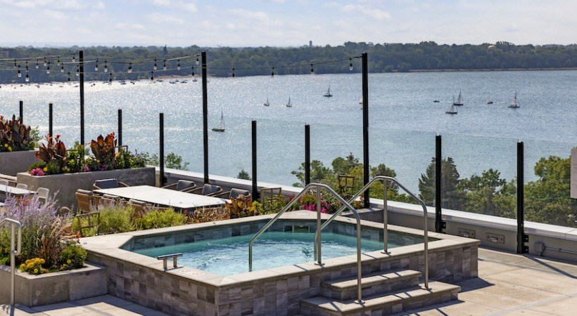 A pool with a hot tub and a view of boats on the water.