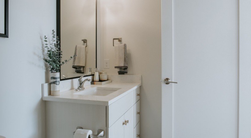 A white bathroom vanity with a mirror above it.