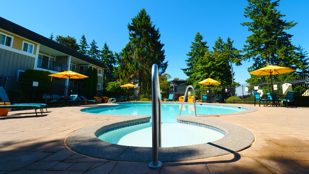 A swimming pool surrounded by trees and umbrellas.