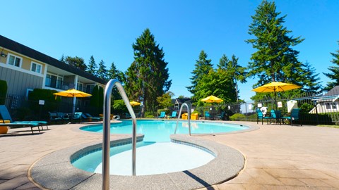 A swimming pool surrounded by trees and chairs.