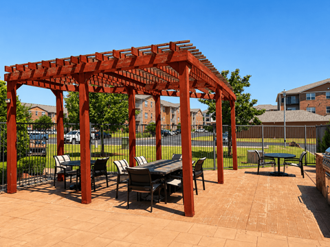 A red pergola with a table and chairs underneath it.
