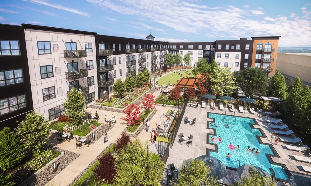 The Collection at Highland Bridge Apartment Homes complex courtyard with a pool, lounge chairs, and people relaxing. Pathways are lined with trees and colorful flowers under a blue sky.