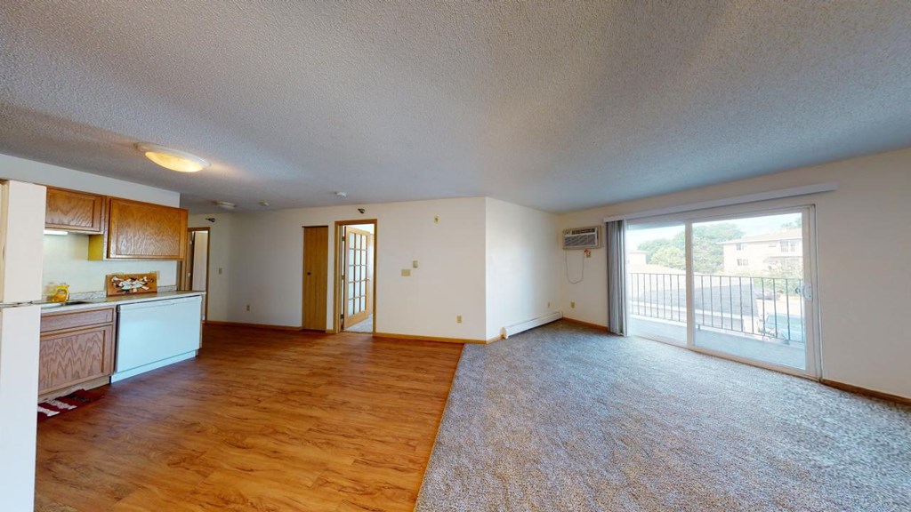 A spacious living room with a sliding glass door leading to a balcony.