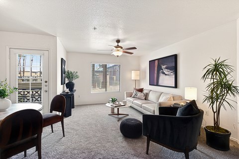 A living room with a couch, chairs, and a ceiling fan.