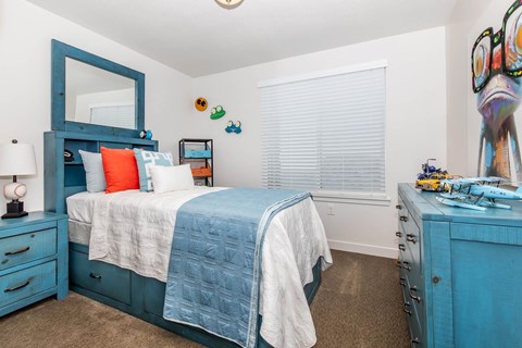 A bedroom with a blue bed and a mirror.