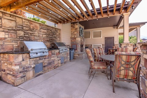 A patio with a table and chairs and a stone wall.