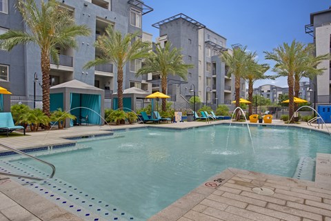 A pool surrounded by palm trees and lounge chairs.