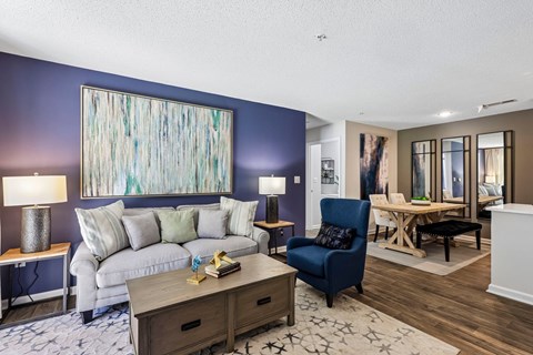 A living room with a white couch, a blue chair, and a wooden coffee table.