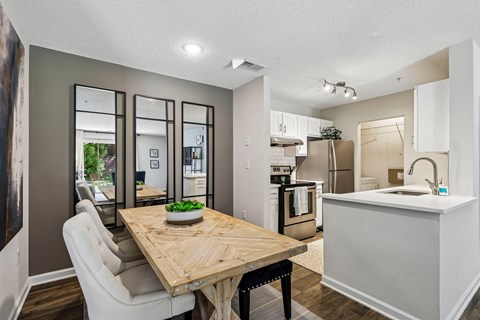 A modern kitchen with a wooden table and white chairs.