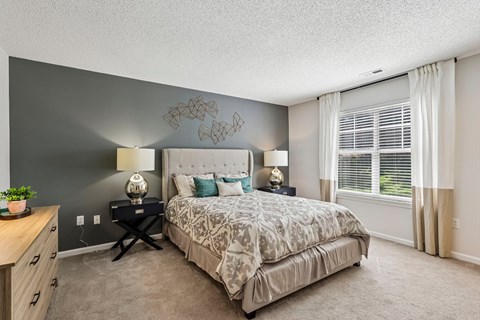 A bedroom with a bed, nightstands, and a plant.