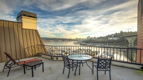 a balcony with a view of a river and chairs and tables