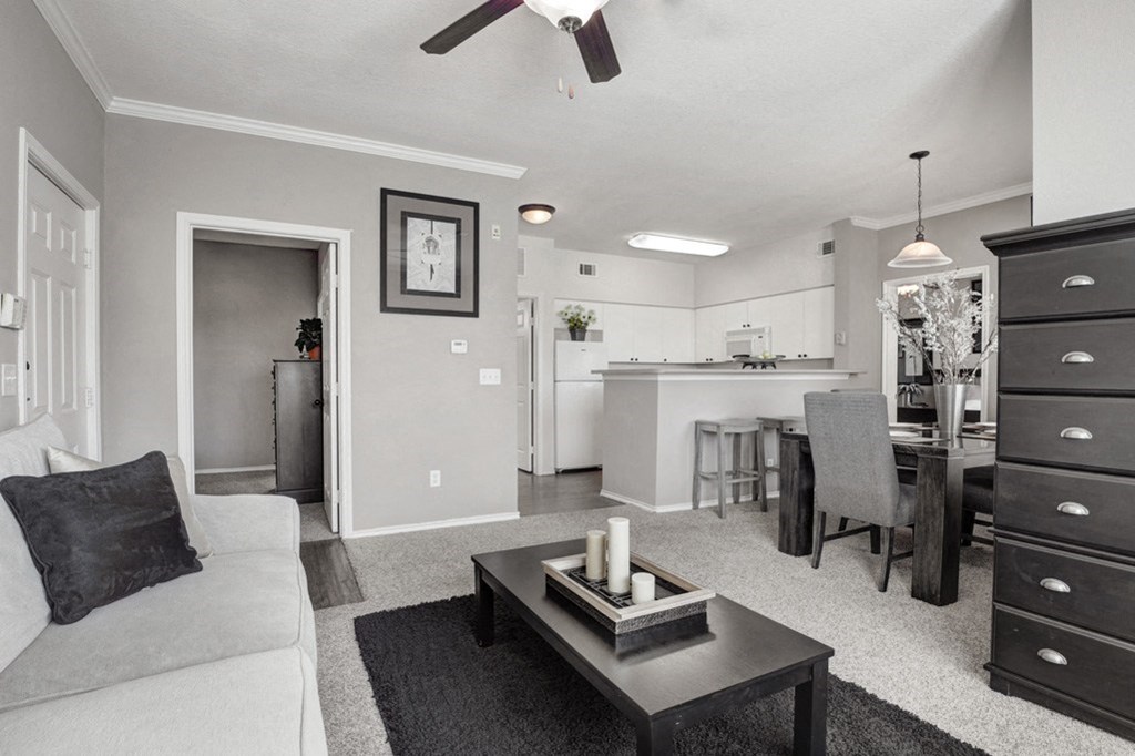 a black and white photo of a living room with a kitchen in the background