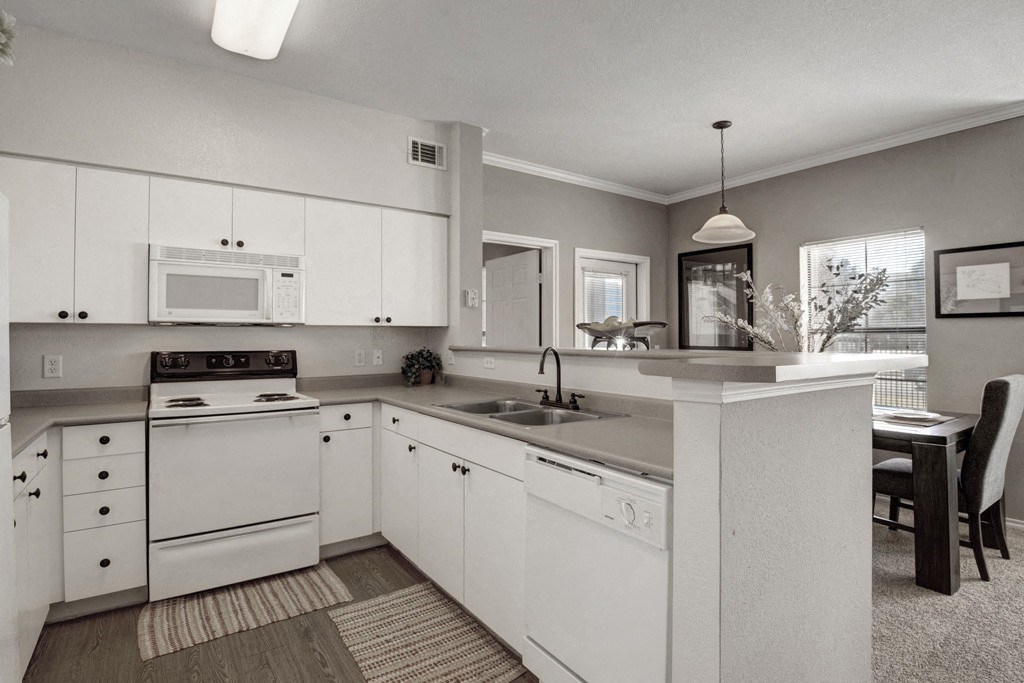 a black and white photo of a kitchen with white appliances and white cabinets