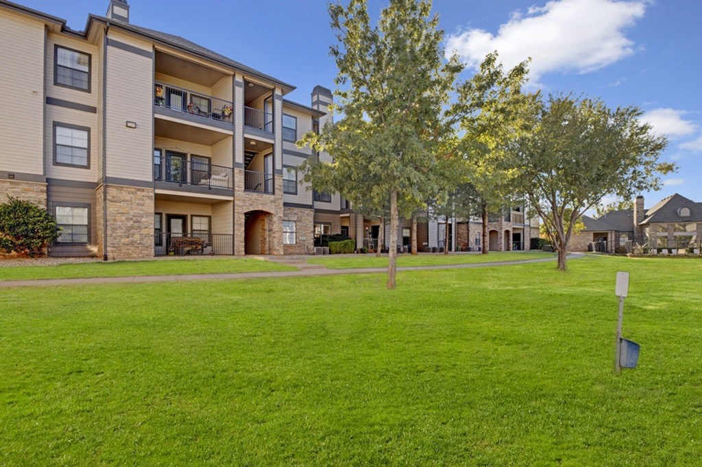 a grassy area with trees in front of a building