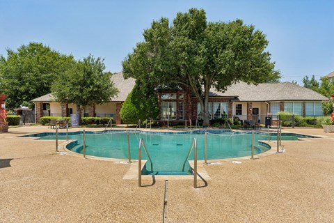A pool surrounded by a fence and trees in front of a house.