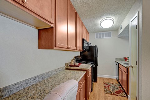 A kitchen with a black refrigerator and wooden cabinets.