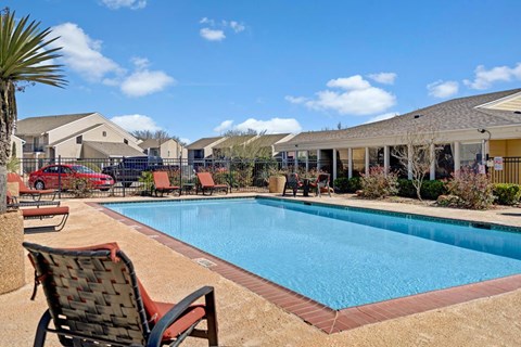 A sunny outdoor pool area at Acacia Park featuring a sparkling swimming pool, comfortable lounge seating, open sightlines, and a relaxed community vibe ideal for warm-weather enjoyment.