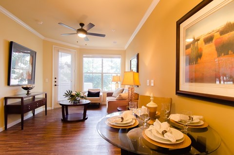 A dining room with a glass table set for two.