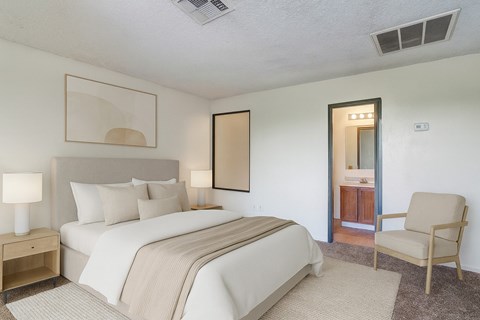 A bedroom with a large bed and a chair.
