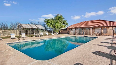 A swimming pool in a backyard with a patio and a gazebo.
