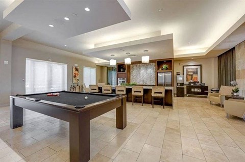 A game lounge here at Cityplace Heights with a pool table, long bar-height counter with stools, pendant lights, tile floors, and adjacent seating areas with soft chairs and tables.