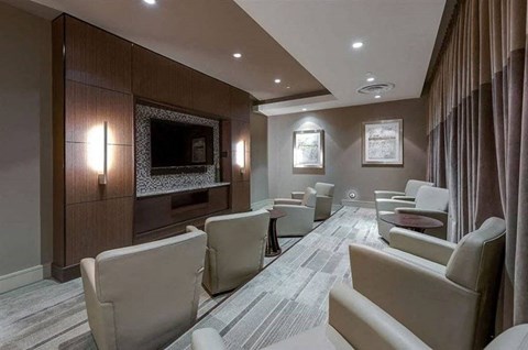 A modern living room with a grey carpet and beige chairs.