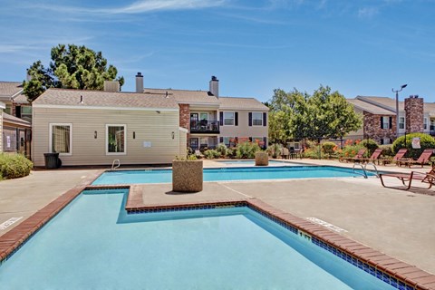 A refreshing outdoor swimming pool here at Cypress Pointe with clear blue water, wide pool decking, and surrounding lounge chairs for relaxing in the sun. A landscaped setting with nearby apartment buildings creates a welcoming, community-focused outdoor space.