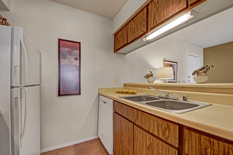 A kitchen with a white refrigerator and wooden cabinets.