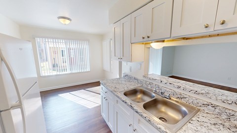 A kitchen with a marble countertop and a double sink.