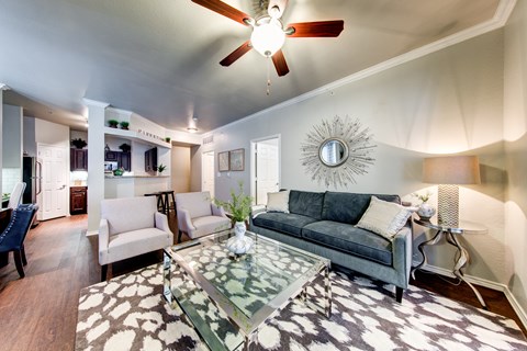 A living room with a grey couch and a glass coffee table.