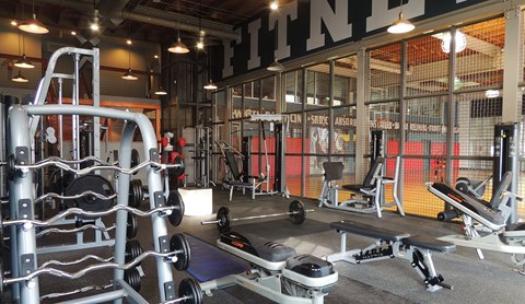 A gym with a variety of equipment including weights and benches.
