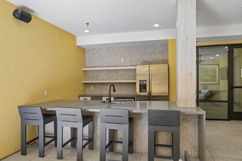 A kitchen with a yellow wall and a table with four chairs.