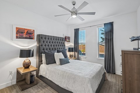 A bedroom with a large bed and a ceiling fan.