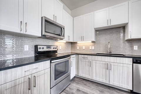 A kitchen with white cabinets and a black counter top.