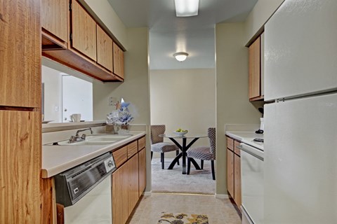 A kitchen with wooden cabinets and a table with chairs.