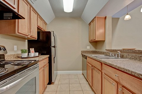 A kitchen with brown cabinets and a black refrigerator.