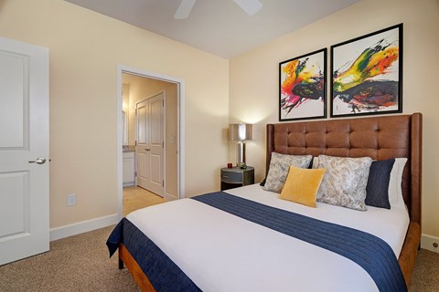 A bedroom with a large bed and two paintings on the wall.
