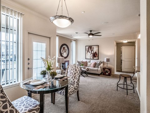 A well-lit living room with a dining table set for two.