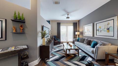 A living room with a grey couch and a striped rug.