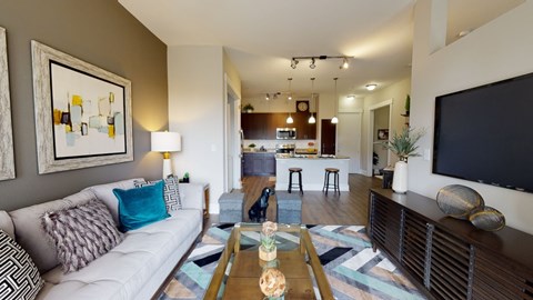 A living room with a white couch and a painting on the wall.