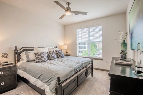 A bedroom with a large bed and a ceiling fan.