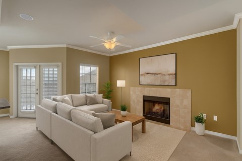A living room with a beige couch, a fireplace, and a painting on the wall.