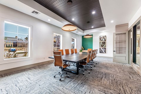 A conference room here at Monterra Village with a long dark table, brown leather swivel chairs, green accent wall, black ceiling detail, and large bright windows along the side.