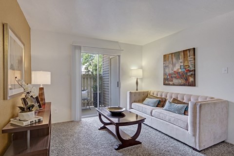 A living room with a couch, coffee table, and a painting on the wall.