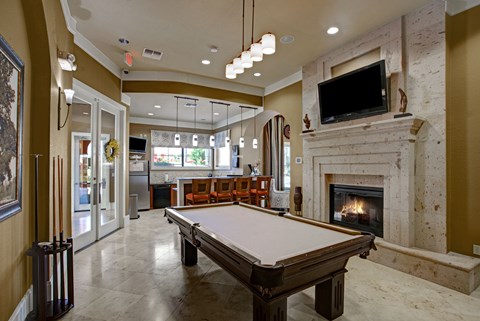 A pool table in a room with a fireplace and a television.