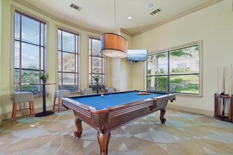 A pool table in a room with a television and a window.