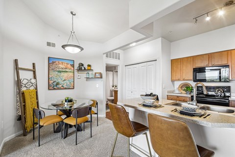 A kitchen with a table and chairs in the foreground and a painting hanging on the wall.