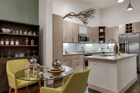 A modern kitchen with a glass table and yellow chairs.