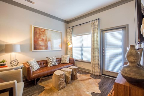A living room with a brown leather couch and a cowhide rug.